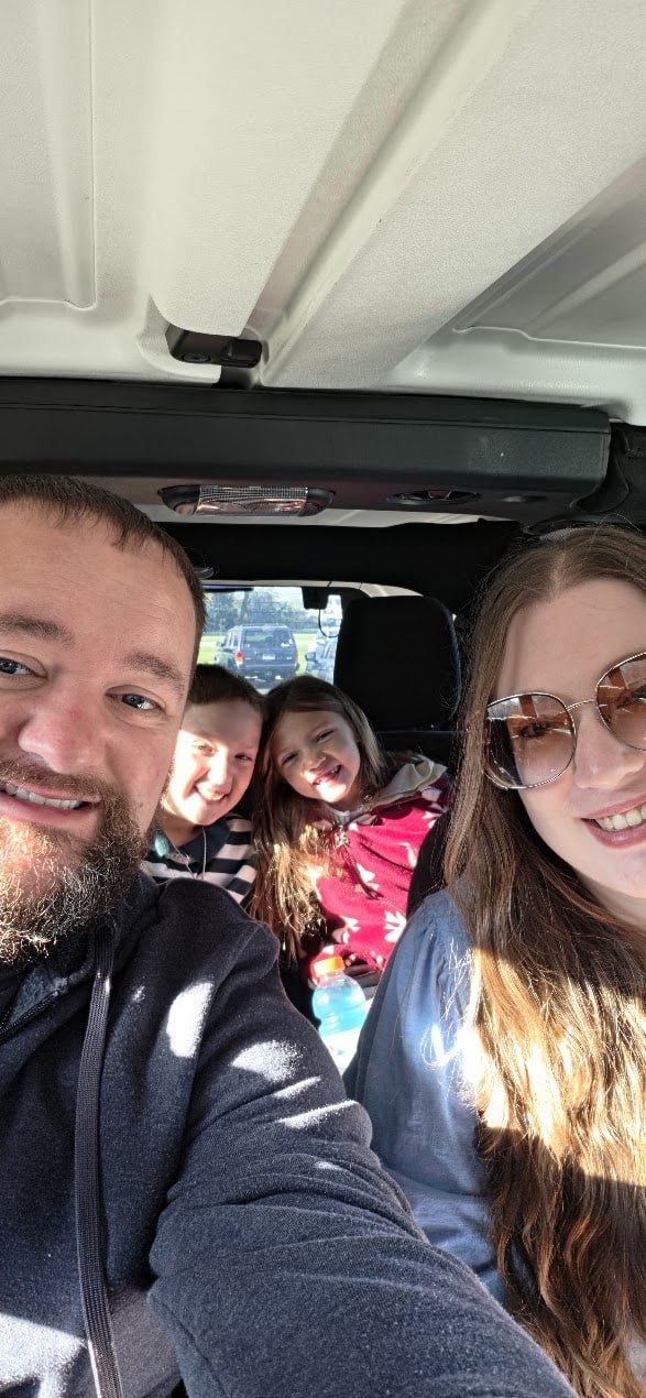 Matthew, Kellie, and family smiling together in the car