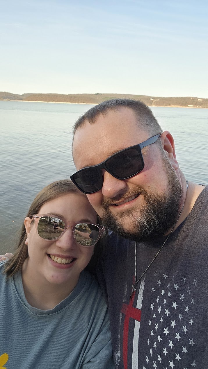 Matthew and Kellie together by the lake wearing sunglasses